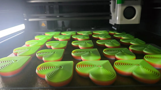 Bambu Lab 3D printer printing heart-shaped fidgets for AllHeartWarriorsMatter